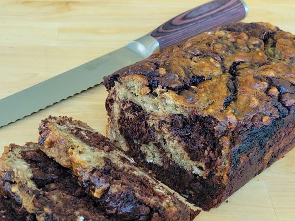 A loaf of chocolate banana bread on top of a wooden cutting board.