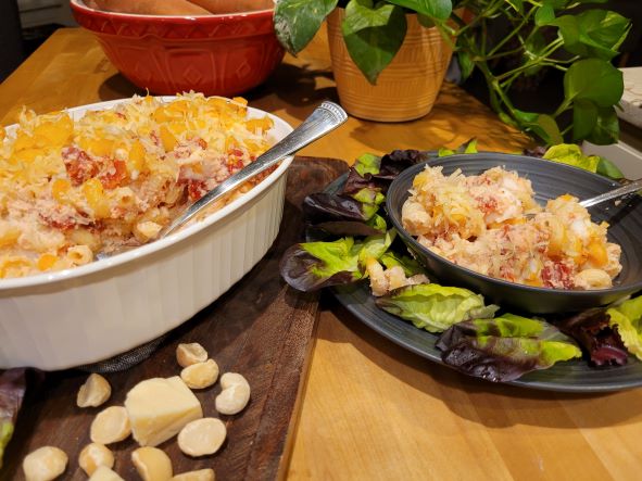 casserole of baked pasta and bowl with serving of pasta surrounded by salad leaves