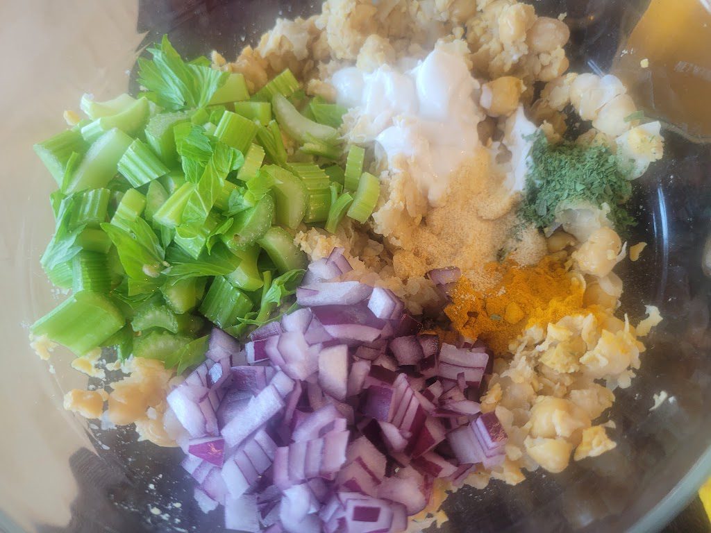 A bowl of food with onions, broccoli and other ingredients.
