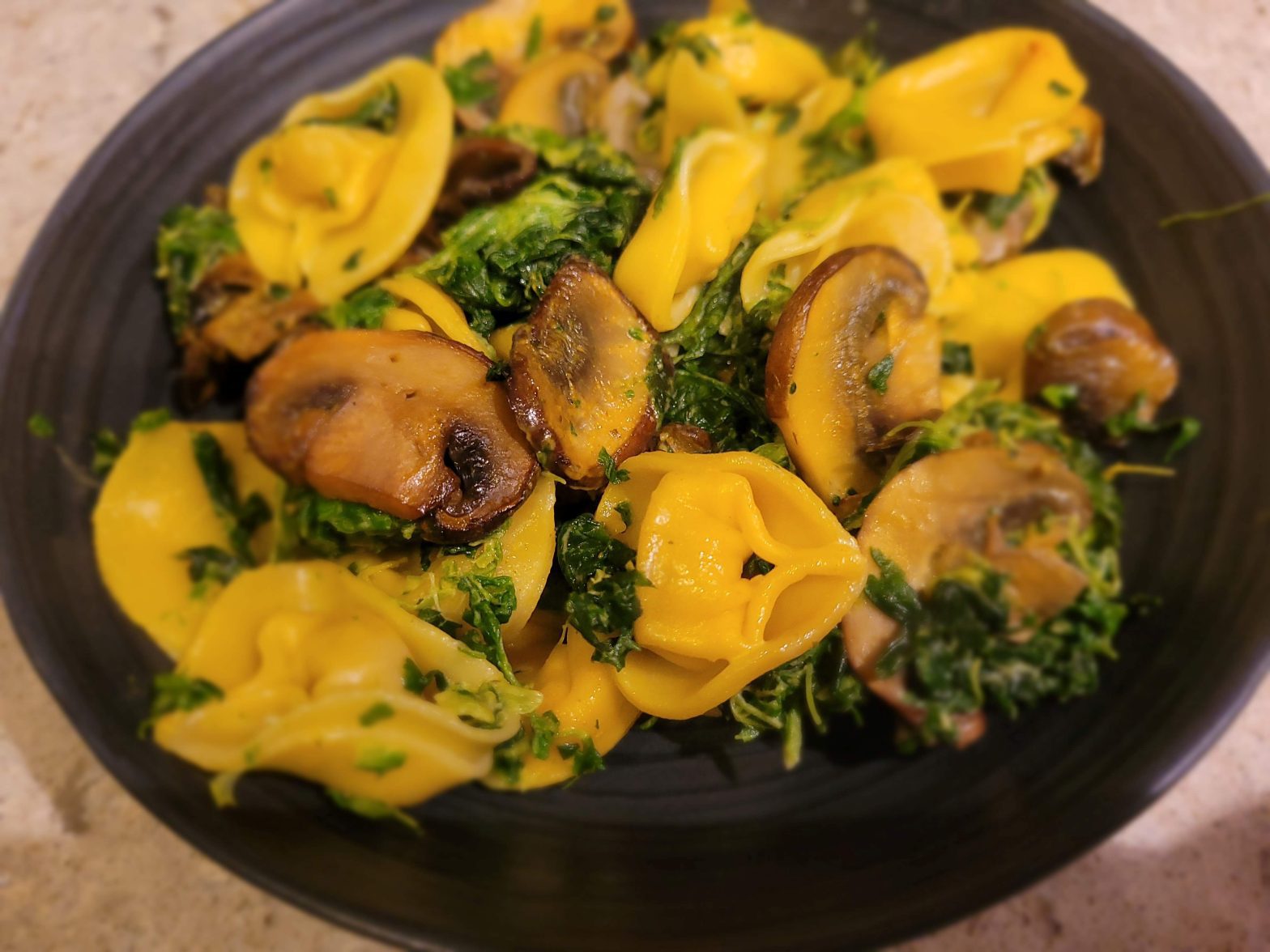 A bowl of pasta with mushrooms and broccoli.