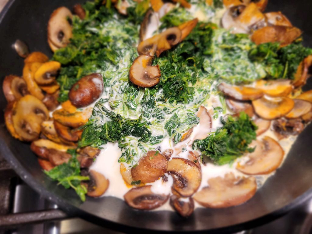 A pan of food with mushrooms and greens.