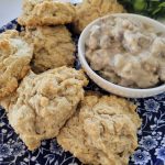 Biscuits on a plate with small bowl of veggie sausage gravy