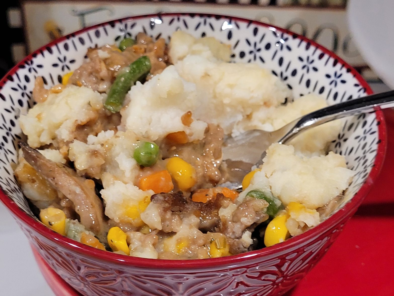 A bowl of food with meat and vegetables.
