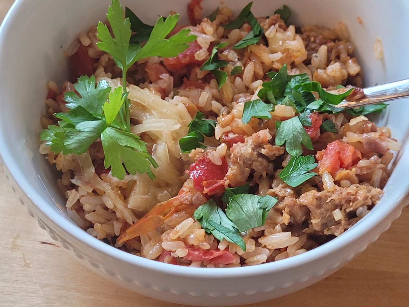 A bowl of rice and meat with parsley.