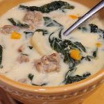 A bowl of soup with sausage and spinach.
